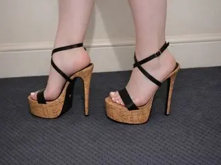 PoppyclaireX shows her bare legs and feet while wearing black strappy high-heeled sandals with cork platforms.