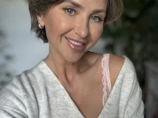 PoshGirlPippa — PoshGirlPippa smiles at the camera wearing a grey v-neck top and pink lace lingerie straps.