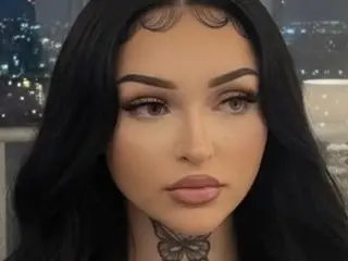 PrettyPrincess24 has long black hair and a butterfly tattoo on her neck, looking directly at the camera with a neutral expression.