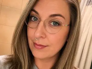 PussyCupcake wearing glasses and a nose ring, looking at the camera with long blonde hair.