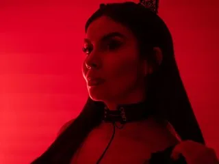 RebecaPierce poses against a red background wearing a black choker and a dark tiara in her hair.