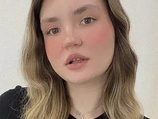 Reneswee poses close-up with her long blonde hair down, showing her face and shoulders against a plain light background.