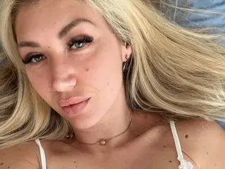RidingChloe poses close-up, looking at the camera with her long blonde hair framing her face and a thin necklace around her neck.