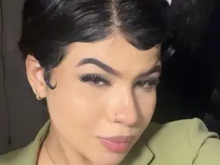 Rosalie_Bliss poses close-up with her dark hair styled in a short wave, wearing a light green top or jacket.