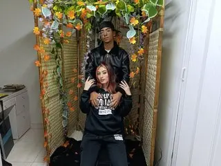 Young couple in casual streetwear posing inside a floral bamboo photo booth with a romantic mood.