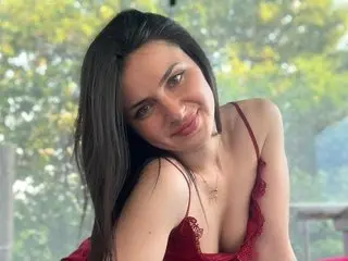 SELLYINA poses with a smile, showing her long dark hair and cleavage while wearing a red lace top.