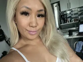 SIAonCamera poses with her long blonde hair down, wearing a white bra or top while looking directly at the camera.