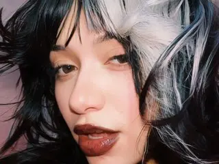 Saenxx looks directly at the camera with her dark hair partially covering her face.