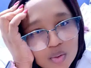 Sanuche_26 wearing glasses and looking into the camera with her hand on her head.