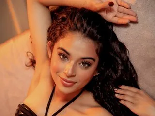 SaraMonserrat lies back with her arms raised, wearing black lingerie and showing her long dark hair.
