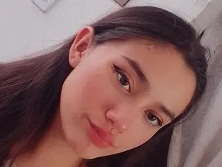 Sarah_World shows her face and long dark hair in a close-up shot, looking directly at the camera with a soft expression.