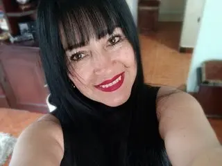 Sarahteikus smiles with her long black hair and bangs, wearing a black sleeveless top while looking directly at the camera.