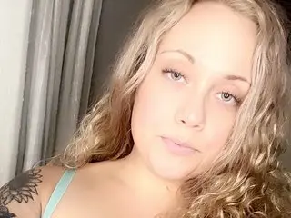 Sarajane19 shows her blonde, wavy hair and bare shoulders in a close-up selfie shot.
