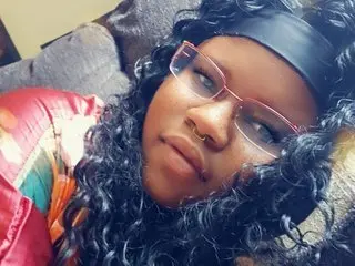 SassySarah1995 poses with a close-up view of her face and dark curly hair while wearing a black headband.