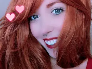 Scarlett_Skye shows off her long red hair and bright smile in a close-up selfie.