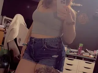 Sdjb1621 poses in a grey crop top and denim shorts, holding her phone for a mirror selfie.