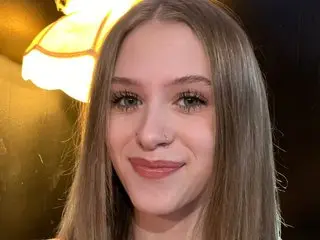 Selene777 poses with a smile, showing her long blonde hair and a small nose piercing in a close-up headshot.