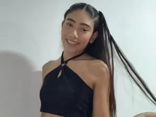 SeleneMarrow smiles while posing in a black halter top, showing off her long dark hair and bare shoulders against a plain white background.