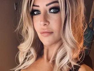 SensationalMya77 poses for a close-up selfie, showing off her blonde hair and heavy smoky eye makeup.