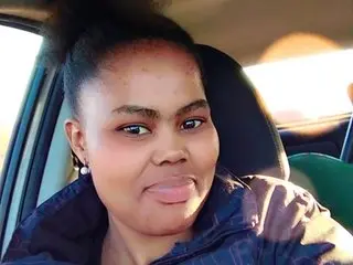 SensualAlly sticks her tongue out, showing her face and hair while wearing a dark jacket in a car seat.