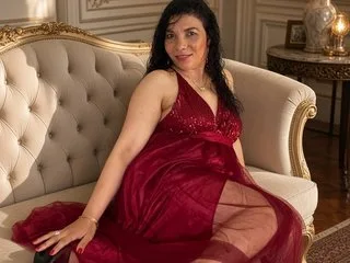 SerenaHoustonn sits on a white tufted sofa wearing a red lace dress.