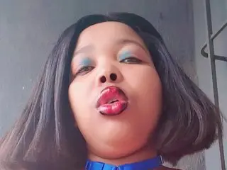 SexyChubbyxx29 pouts her red lips and looks into the camera with blue eyeshadow and dark hair.