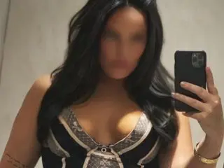 SexySadiieXX poses in a mirror selfie wearing a black and white cut-out top, showing her cleavage and long dark hair.