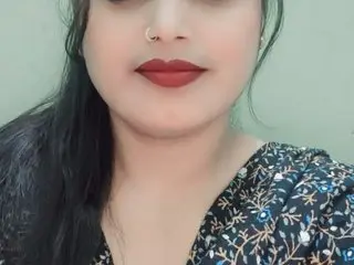 Sexybegam91 looks at the camera with long dark hair and red lipstick, wearing a black patterned top against a plain light background.