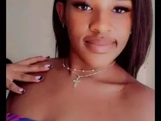 Sexyred2118 poses with her long dark hair down, wearing a gold chain necklace and a purple top, showing her bare shoulders and neck.