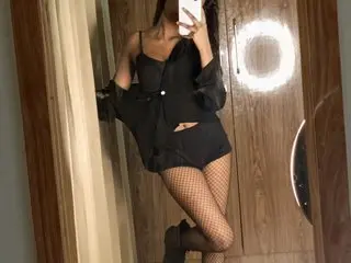 ShanayaKapoor poses in a dark blue satin chemise and black fishnet stockings, showing her legs and cleavage in a mirror selfie.
