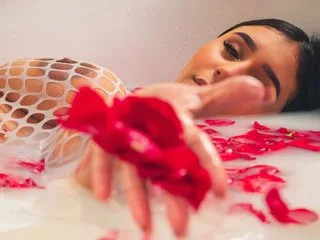 SheylaBakerr relaxes in a milky white bubble bath surrounded by red rose petals.