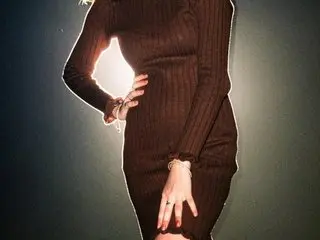 Elegant woman in a brown ribbed knit midi dress posing against a dark moody background.