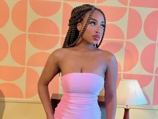 Sia_37 poses in a strapless pink dress against a pink and cream patterned wall.
