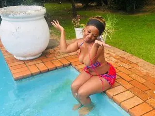 Smiling woman in a colorful bikini sitting by a garden swimming pool on a sunny day.