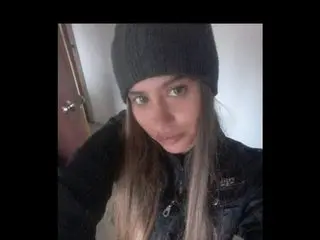 SilvannaReed poses with long blonde hair, wearing a black beanie and a black top against a plain wall background.