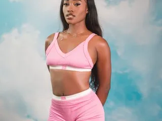 Skylar_Smiith poses in a pink ribbed sports bra and matching shorts against a blue cloudy background.