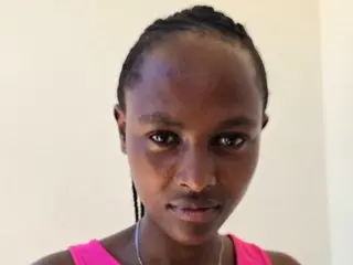 Slimy_sleek looks directly at the camera with a close-up headshot, showing her dark hair pulled back and her bare shoulders.