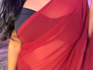 SobnamHayat poses in a red sheer saree that shows her skin through the fabric, paired with a black top.