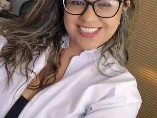 SofiaFile smiles at the camera wearing black glasses and a white zip-up jacket over a black top.