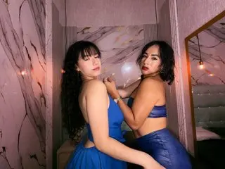 Two beautiful women in elegant blue evening dresses posing in a luxurious marble room with moody lighting.