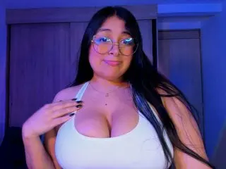 Sofiarodrigue poses with long dark hair and glasses, wearing a white tank top that shows off her cleavage.