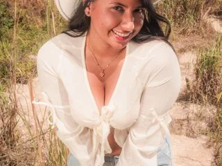 SolSinger smiles in a white tie-front blouse and cowboy hat while standing in a grassy field.