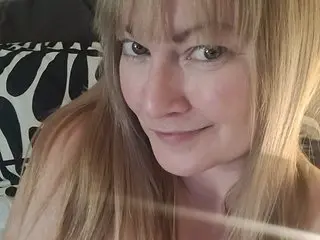 Solesticia poses with a slight smile, showing her long blonde hair and bare shoulders in a close-up shot.