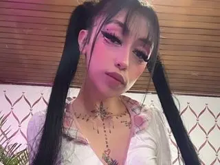 SophiexBunny poses with long pigtails and a low-cut white top, showing off her chest and neck tattoos in a close-up shot.