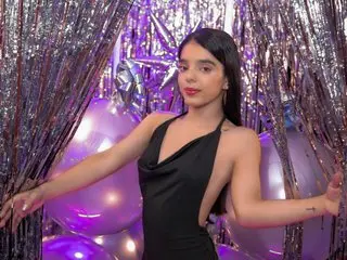 SophiiaBlazee poses in a black dress against a backdrop of silver tinsel and purple balloons.
