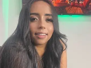 Smiling young woman with long dark hair posing for a portrait in a brightly lit indoor setting.