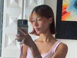 Stefanny_vv poses for a mirror selfie, wearing a pink tank top with her hair styled in a short bob.