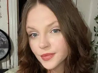 StonerLeighh poses for a close-up headshot, showing her long brown hair and light eyes against a soft indoor background.