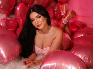 Smiling young woman in a pink strapless top relaxing amidst pink heart balloons in a romantic dreamy setting.