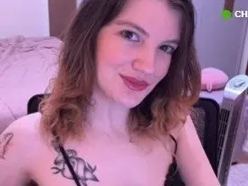 SweetLuci poses with her long brown hair down, wearing a black lace bra that shows off her cleavage and shoulders.